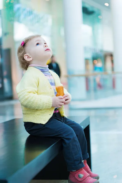 Söt liten flicka äter kex kaka på bänk — Stockfoto