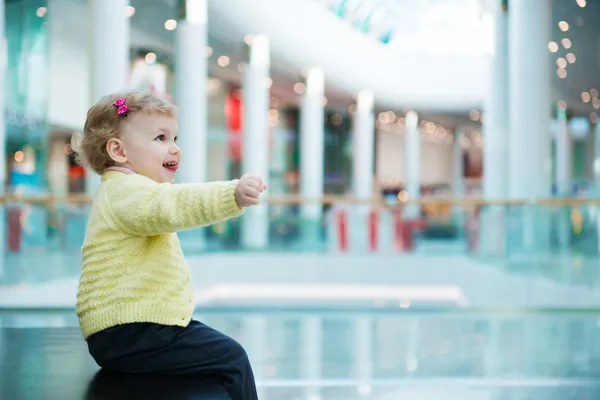 Linda niña sentada en el banco en el centro comercial — Foto de Stock