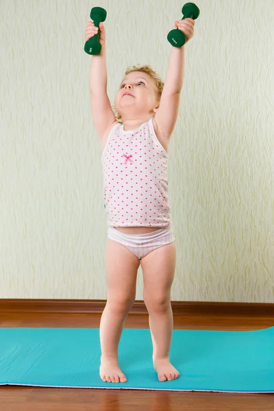 Kleines Mädchen hebt Hanteln hoch — Stockfoto