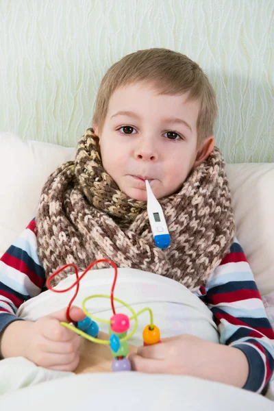 Sick little boy lying in bed with thermometer — Stock Photo, Image