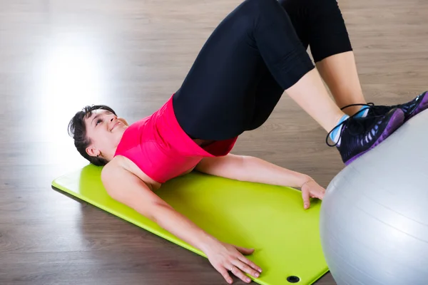 Entrenamiento de fitness de mujer joven en gimnasio con fitball — Foto de Stock