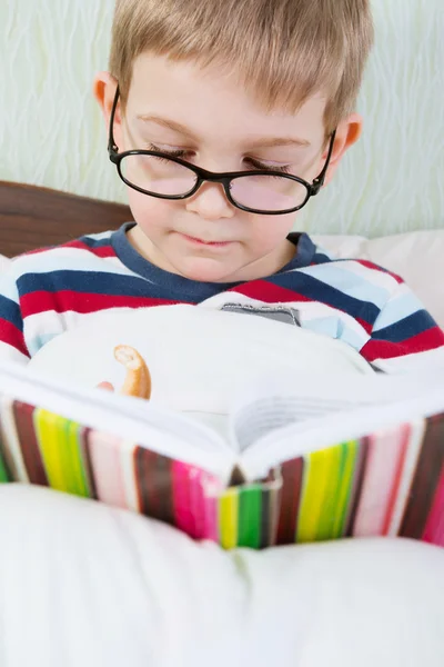 Kleiner süßer Junge liest Buch im Bett — Stockfoto