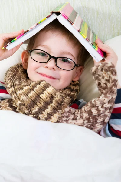 Lindo chico con libro por encima de su cabeza — Foto de Stock