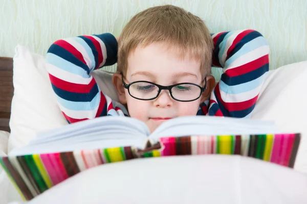 Küçük sevimli çocuk okuma kitabı yatakta — Stok fotoğraf