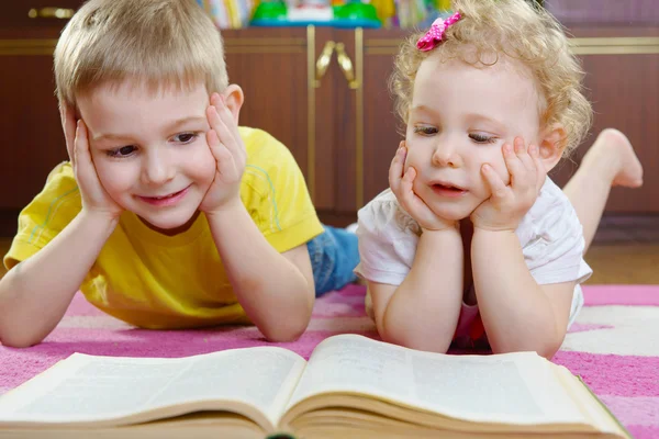 Söta lilla bror och syster läser bok på golvet — Stockfoto