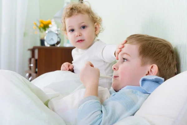 Маленькая девочка и ее больной брат лежат в постели — стоковое фото