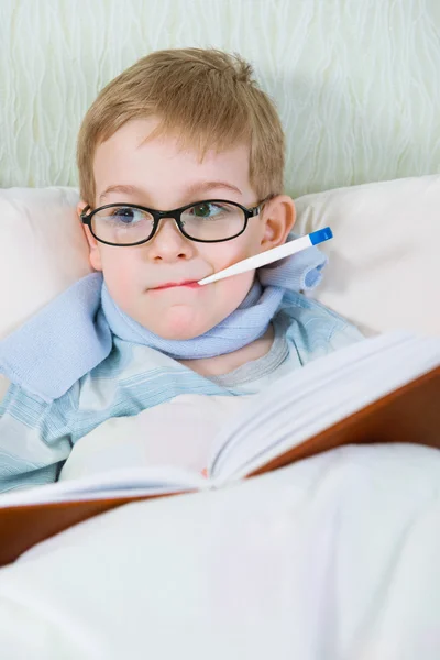 Chory chłopczyk, leżąc w łóżku z termometrem — Zdjęcie stockowe