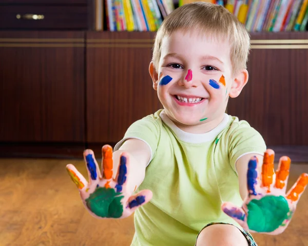 Sorrindo menino mostrando as mãos em tintas — Fotografia de Stock