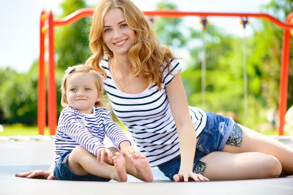 Madre joven e hija pequeña jugando en el patio de recreo —  Fotos de Stock