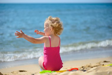 sevimli küçük kıvırcık saçlı kız kumu ile oynamak