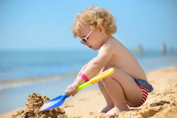 Menina bonito em óculos de sol brincando com areia — Fotografia de Stock