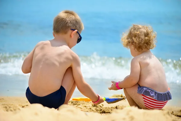 Little brother and sister playing with sand — Stock Photo, Image