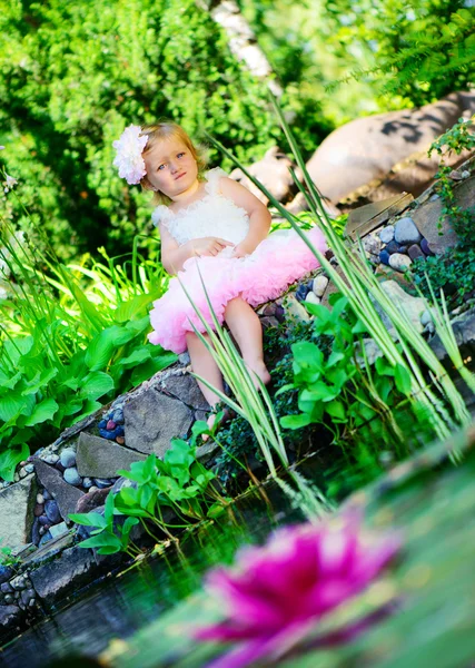 Llittle girl in ballerina tutu sitting at pond — Stock Photo, Image