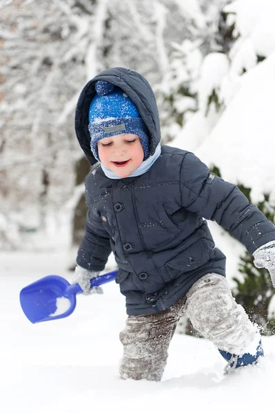 Niño pequeño con pala jugando en la nieve — Foto de Stock