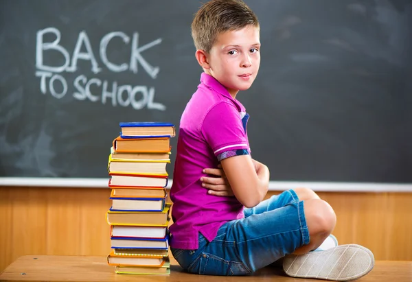 Carino scuola ragazzo seduta con libri in aula — Foto Stock