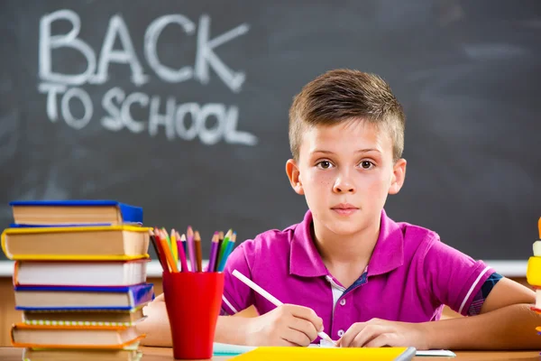 Söt skola pojke studerar i klassrummet — Stockfoto