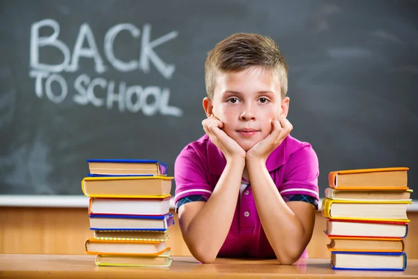 Söt elev med böcker i klassrummet — Stockfoto