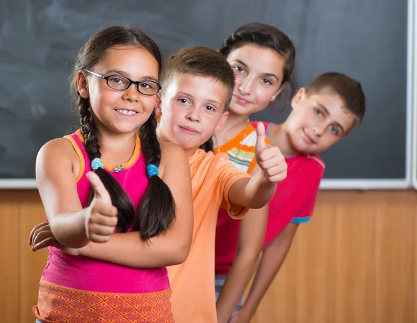 Fyra leende skolbarn står i klassrummet — Stockfoto