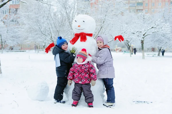 Barn bygga snögubbe i trädgården — Stockfoto