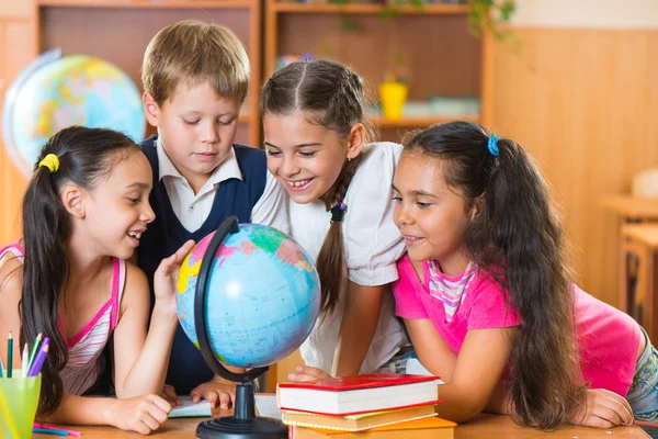 Porträt von süßen Schulkindern, die auf Globus schauen — Stockfoto