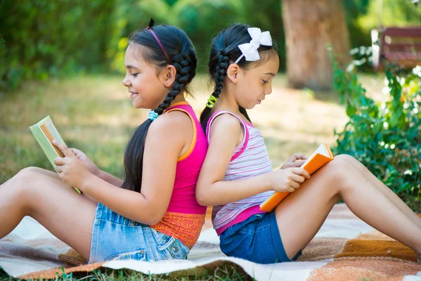 Zusters lezen boek in zomer park — Stockfoto