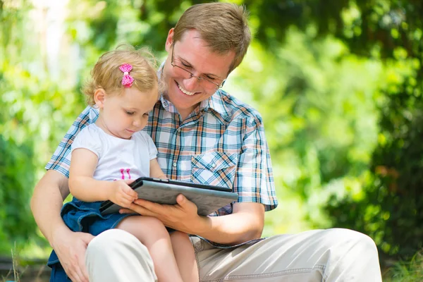 Молодой отец и маленькая дочь читают — стоковое фото