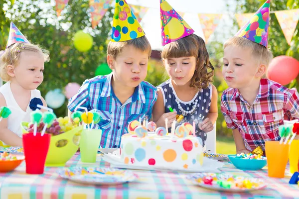 Kids blowing candles on cake at birthday party Stock Image