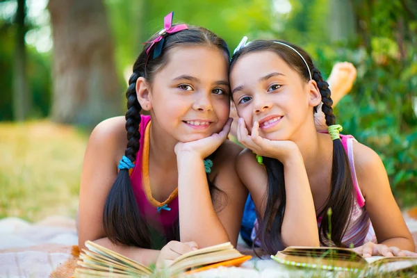 Porträt zweier hispanischer Schwestern, die im Park lesen — Stockfoto