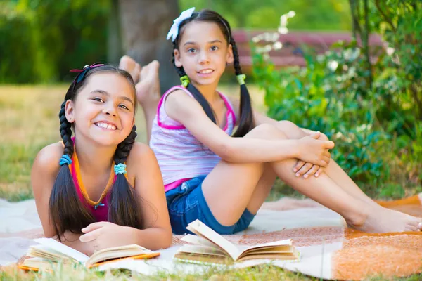 Hermanas hispanas felices leyendo en el parque —  Fotos de Stock