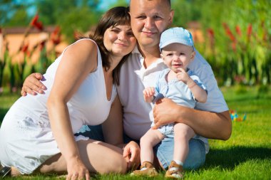 mutlu genç aile yeşil çimenlerin üzerinde poz