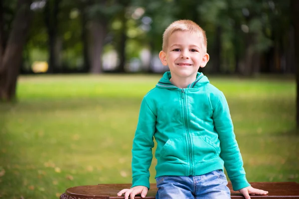 Mignon petit garçon assis sur le banc — Photo