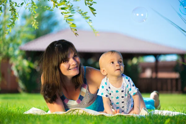 Joven madre e hijo pequeño mirando burbujas de jabón — Foto de Stock