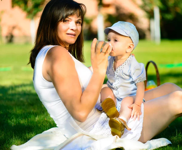 Madre joven alimentando a su pequeño hijo con biberón — Foto de Stock