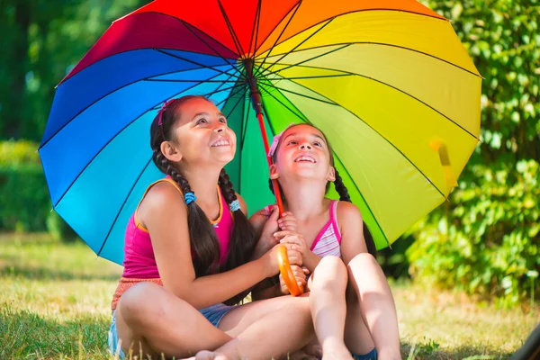 Happy sisters under colorful umbrella in park — Stock Photo, Image