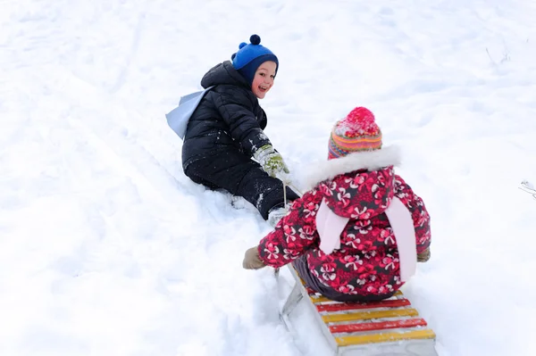 Mignon garçon tirant son soeur sur luge — Photo