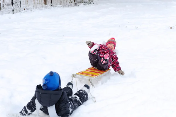 Cute boy pulling his sister on sled — Stock Photo, Image