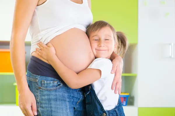 Menina abraçando mãe grávida — Fotografia de Stock