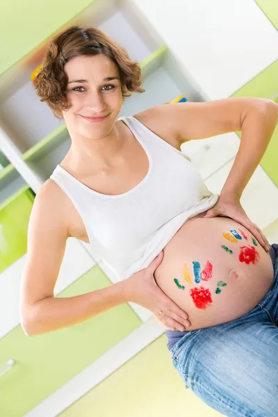 Счастливая беременная девушка с пальмовыми штампами на животе — стоковое фото