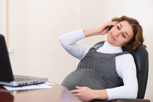 Молодая беременная женщина в офисе — стоковое фото