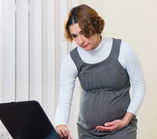 Jeune femme enceinte travaillant au bureau — Photo