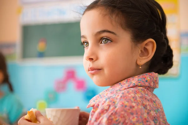 Süßes hispanisches Mädchen mit einer Tasse Milch in der Kita — Stockfoto