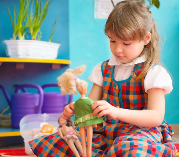 Cute girl playing with toy doll at kindergarten — Stock Photo, Image