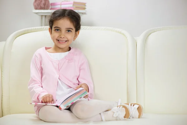 Bonito sorrindo hispânico menina leitura livro — Fotografia de Stock