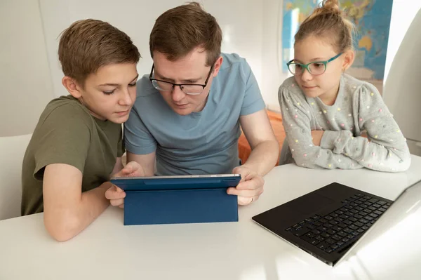 快乐的年轻父亲在家里用笔记本电脑和十几岁的孩子一起学习 — 图库照片