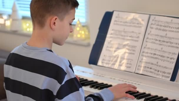 60Fpsビデオの十代の男の子の演奏ピアノと練習新しいメロディー — ストック動画