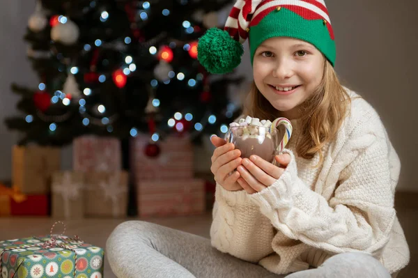 Linda Niña Con Sombrero Divertido Sentado Cerca Del Árbol Navidad Imagen de stock