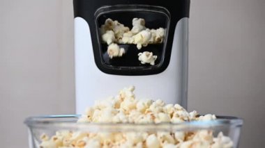 Slow motion video of popcorn machine producing popcorn out of corn into bowl