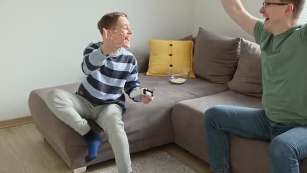 60Fps Відео Щасливого Молодого Батька Грає Своїм Сином Відеоігри Контролерами — стокове відео