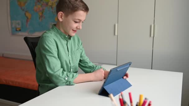 幸せと笑顔ティーン男の子オンラインで話すタブレットを介して彼のクラスメートとともにコロナウイルスの隔離中に — ストック動画