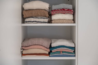 Pastel giysiler dolabın raflarında güzelce katlanmış.